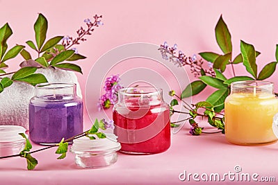 Scented candles for Spa and home with green leaves on a pink background Stock Photo