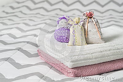 Scented sachets and fragrant pouch figure of a girl. Bags filled with lavender in bedroom. Towels on bed. Stock Photo