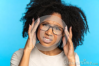 Sceptical mistrustful African American girl adjusts glasses, suspicious looking at camera. Studio. Stock Photo