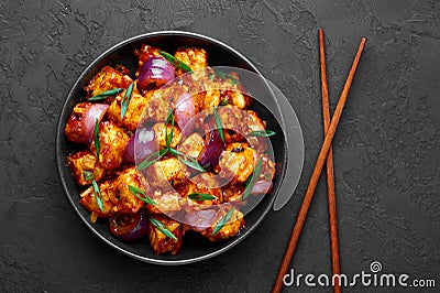 Schezwan Paneer in black bowl at dark slate background. Schezwan Paneer is indo-chinese cuisine dish Stock Photo