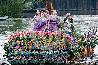 Colourful canal parade of flower and vegetables decorated boats with cheerful dressed up singing and dancing people Editorial Stock Photo