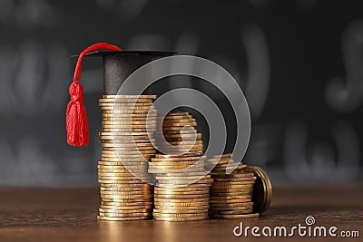 Scholarship concept. Coins and graduation cap on wooden table Stock Photo
