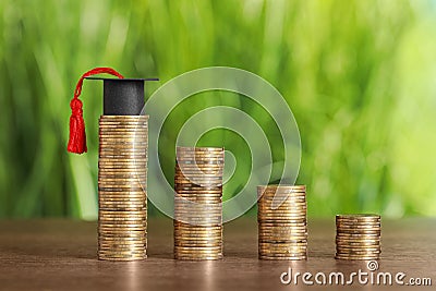 Scholarship concept. Coins and student graduation cap on wooden table Stock Photo