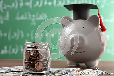 Scholarship concept. Glass jar with coins, piggy bank, graduation cap and dollar banknotes on wooden table Stock Photo