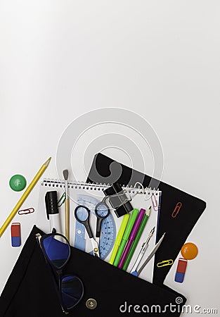 School background. Office supplies in an open black backpack. White background, free space for text Stock Photo