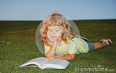 School boy with a book having a rest outdoor. Child boy with a book in the garden. Kid is readding a book playing Stock Photo