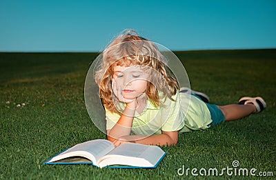 School boy with a book having a rest outdoor. Child boy with a book in the garden. Kid is readding a book playing Stock Photo