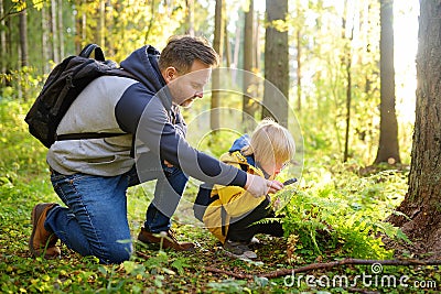 School boy and his father hiking together and exploring nature with magnifying glass. Little boy and dad spend quality family time Stock Photo