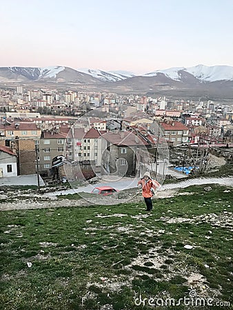 A school child walking at grass and behind Nigde city center Editorial Stock Photo