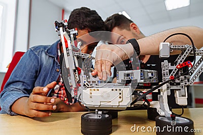 Mixed Racial group of School children controlling robotic machine with remote control together teacher. Creative kids Stock Photo