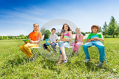 School children hold notebooks and sit on chairs Stock Photo