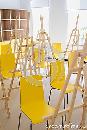 School drawing class, lots of empty easels and yellow chairs Stock Photo
