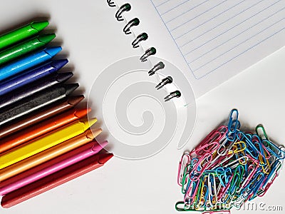 colored metalic clips, colored crayon row and note book with spiral, background and texture Stock Photo