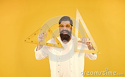 School of engineering. Happy engineer or designer. Smart engineer holding triangles on yellow background. Teaching Stock Photo