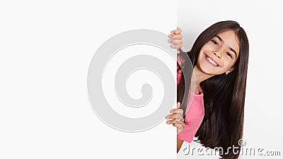 School girl looking behind blank board with copy space Stock Photo