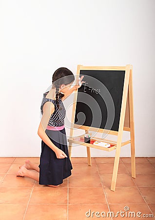School girl writing Albert Einstein equation on blackboard Stock Photo