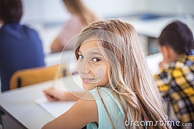 School girl writing on paper in classroom Stock Photo
