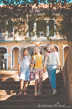 School girls going to home after school. Three little school girls walking and holding hands Stock Photo