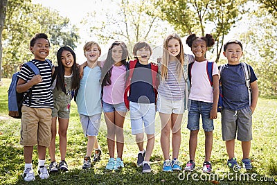 School kids stand embracing in a row outdoors, full length Stock Photo