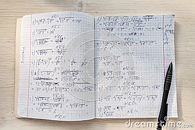 School notebook in a cage and pen with a mathematical calculation. High school notebook on the table Stock Photo