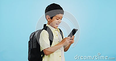 School, phone or kid on social media in studio typing to chat, play mobile games or download app. Blue background Stock Photo