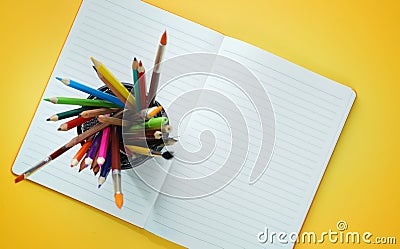 School Stationary in Basket on Opened Book Top View Yellow Background Stock Photo