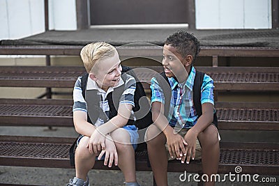 School Students talking together while sitting on the stairs at school Stock Photo