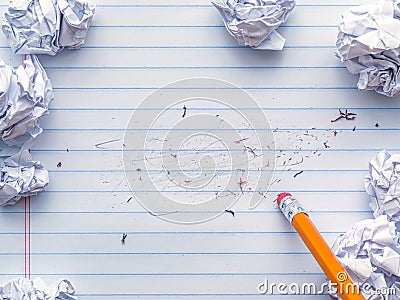 School supplies of blank lined notebook paper with eraser marks and erased pencil writing, surrounded by balled up paper and a Stock Photo