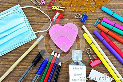School supplies , a heart shape note pad ,a mouth mask and liquid hand sanitizer Stock Photo