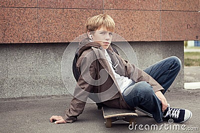 School teen sits on skateboard near school Stock Photo