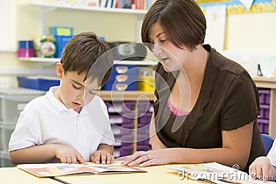 A schoolboy and his teacher reading in class Stock Photo