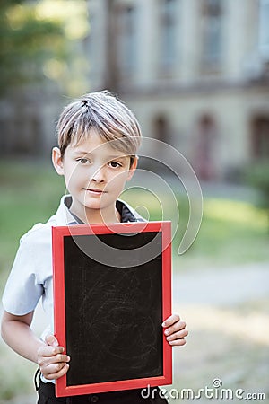 A schoolboy holding a chalk board. Kid holding a black board. Empty space for text. School lessons. Back to school Stock Photo