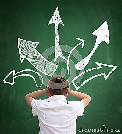 Schoolboy looking in different arrows in different direction Stock Photo