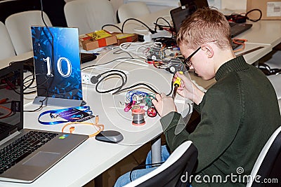 Schoolboy making a robot with the electric soldering iron Editorial Stock Photo