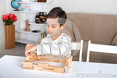 A schoolboy sits on the table and plays in a wooden cons Stock Photo