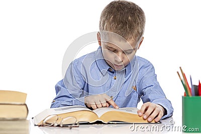 The schoolboy sits at the table and does his homework. Isolated on a white background Stock Photo