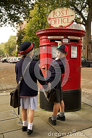 Schoolboy turning while posting letter with sister Stock Photo