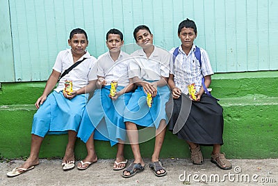 Schoolboys in Tonga. Friendly boys in wraparound skirts eating chips after school. Editorial Stock Photo