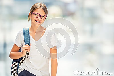 Schoolgirl with bag, backpack. Portrait of modern happy teen school girl with bag backpack. Girl with dental braces and glasses Stock Photo