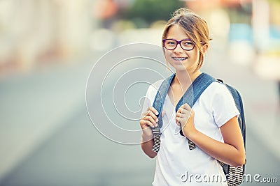 Schoolgirl with bag, backpack. Portrait of modern happy teen school girl with bag backpack. Girl with dental braces and glasses Stock Photo