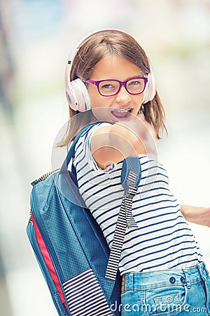 Schoolgirl with bag, backpack. Portrait of modern happy teen school girl with bag backpack headphones and tablet. Stock Photo