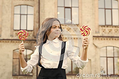 Schoolgirl choosing sweets. Happy kid with sweet candy. Kid child holding lollipops candy outdoors. Happy kid with candy Stock Photo