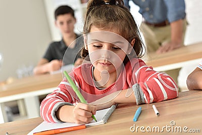 Schoolgirl in class wriitng in notebook Stock Photo