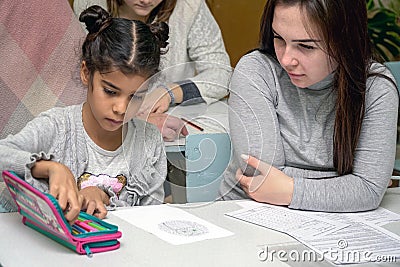 Schoolgirl at a desk with a woman teacher Editorial Stock Photo