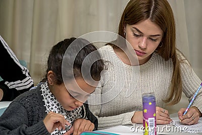 Schoolgirl at a desk with a woman teacher Editorial Stock Photo