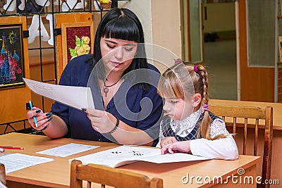 Schoolgirl at a desk with a woman teacher Editorial Stock Photo