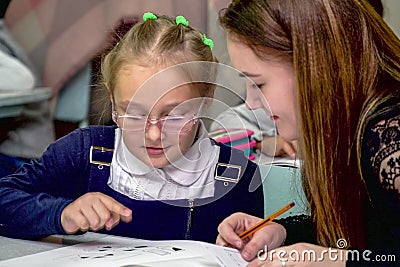 Schoolgirl at a desk with a woman teacher Editorial Stock Photo