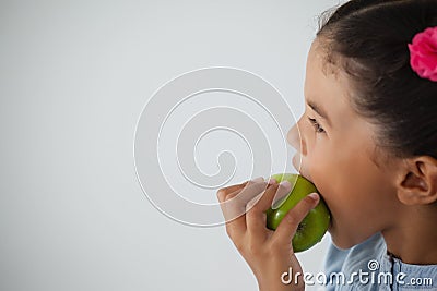 Schoolgirl eating apple against white background Stock Photo