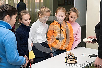 Schoolgirl girls are smiling and looking at a homemade car model Editorial Stock Photo