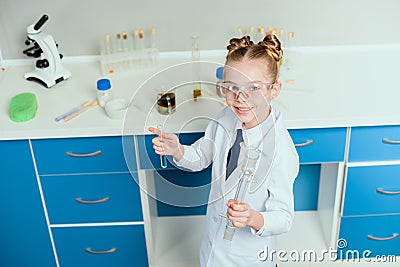 Schoolgirl in goggles holding reagents in flasks in chemical lab Stock Photo